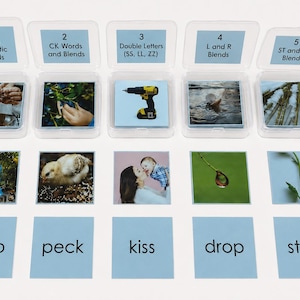 May include: Five clear plastic storage cases containing educational cards labeled 1 through 5 with categories like Long Phonetic Words and Blends. Below are corresponding image cards and word cards including lamp, peck, kiss, drop, and stem.