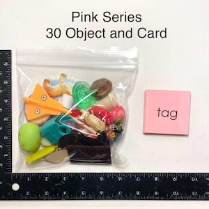 May include: A clear bag containing assorted miniature items, such as a toy plane and a green sweet, alongside a pink card labelled "tag". The image also features the text "Pink Series 30 Object and Card".