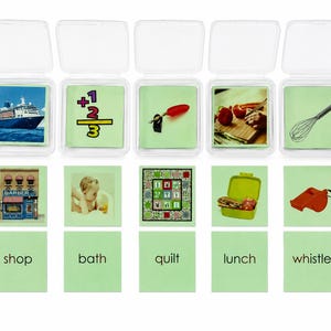 May include: A set of five clear plastic containers holding cards with images of a cruise ship, math symbols, a red chili, vegetables, and a whisk. Below are five green cards featuring images of a barber shop, a bath, a quilt, a lunch box, and a whistle, with the words shop, bath, quilt, lunch, and whistle printed below each.