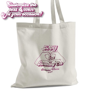 May include: White tote bag with a pink design that says "In My 21st Birthday Era" with a heart shape made of hands. The text "Danielle's Version 2021" is below the design.