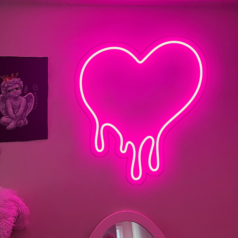 May include: A pink neon sign shaped like a heart with dripping edges. The sign is mounted on a pink wall.