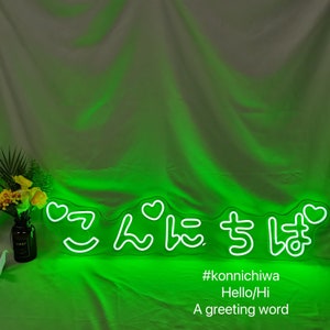 May include: Green neon sign with the Japanese word "Konnichiwa" which means "Hello" in English. The sign also includes hearts and a smiley face. The text below the sign reads "#konnichiwa Hello/Hi A greeting word"