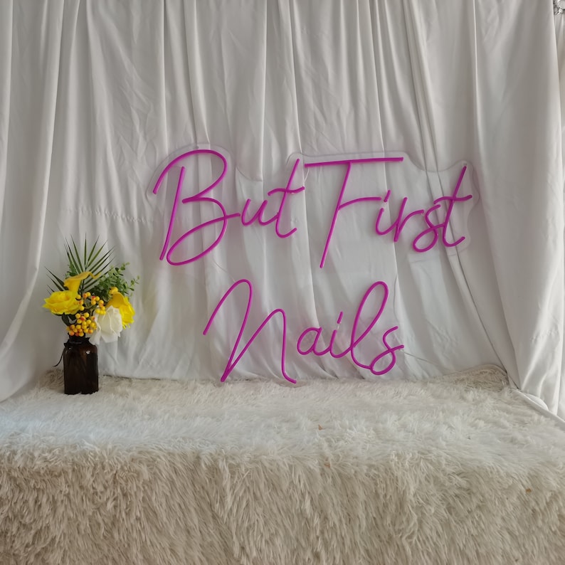 Puede incluir: Letrero de ne&oacute;n rosa con el texto "But First Nails" sobre un fondo blanco.