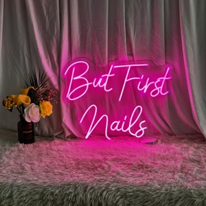 Puede incluir: Letrero de ne&oacute;n rosa con el texto "But First Nails" sobre un fondo blanco.