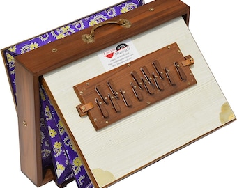 May include: A wooden harmonium musical instrument featuring a brown frame, a white keyboard panel with dark brown keys, and purple bellows with a yellow floral pattern. A white label with the text Kaayna Musicals is attached to the top panel.