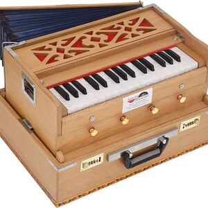 May include: A wooden harmonium with a keyboard, red detailing, and a decorative top. The instrument features a handle and gold-coloured knobs. The bellows are visible at the top, and the keyboard has black and white keys. A musical instrument.