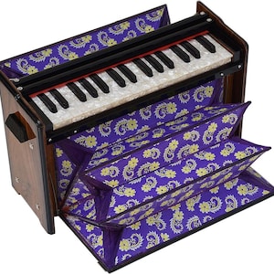 May include: A portable harmonium musical instrument featuring a dark brown wooden frame and a keyboard with white and black keys. The bellows and top panel are covered in a vibrant purple fabric decorated with a repeating yellow floral pattern.