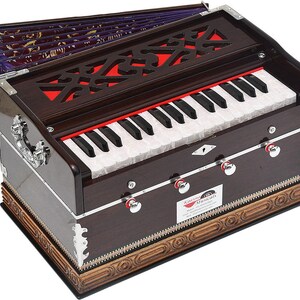 May include: A brown harmonium with a keyboard featuring black and white keys. The instrument has a decorative fretwork design on the top and silver accents. The bellows are visible in the background, and the instrument has a wooden base.