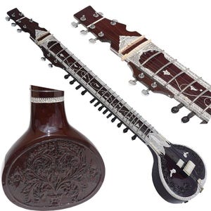 May include: A dark brown sitar, a plucked stringed instrument, with intricate silver inlay and carvings. The instrument features a large, rounded body and a long neck with frets. The headstock has tuning pegs.