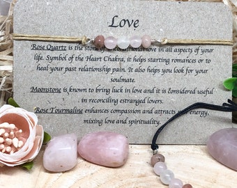 Könnte beinhalten: Ein Set Liebeskristalle mit einer Karte, auf der "Liebe" steht. Die Karte beschreibt die Eigenschaften von Rosenquarz, Mondstein und Rosenquarz. Die Kristalle sind rosa und weiß.