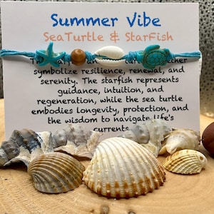 Könnte beinhalten: Ein blaues und weißes Armband mit einem Seestern- und Meeresschildkröten-Anhänger. Das Armband liegt auf einer Holzoberfläche mit Muscheln. Der Text auf der Karte lautet "Summer Vibe Sea Turtle & StarFish" und beschreibt die Symbolik der Anhänger.