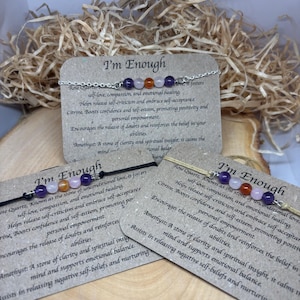 May include: Two bracelets with a silver chain and colorful stones. The bracelets are on a brown background with the text "I'm Enough" and a description of the stones and their meanings.