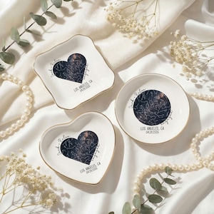 May include: Three white ceramic ring dishes with gold rims. Each dish features a dark blue heart or circle design with a star map, the names "Jack & Rilee", the word "engaged", and the date and location.