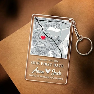 May include: Clear acrylic keychain with a map design and the text "OUR FIRST DATE" and "Anna ♥ Jack". The map features a red heart marking a location. The date "FEBRUARY 14TH 2024" is also printed on the keychain. A silver keyring is attached.
