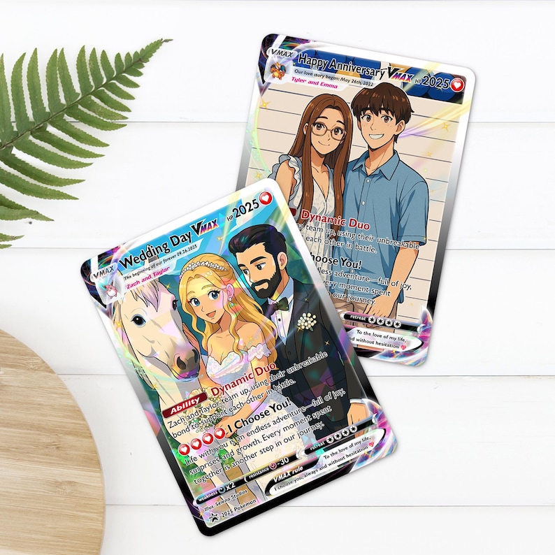 two illustrated cards with cartoon-style characters on them, placed on a white surface next to a plant.