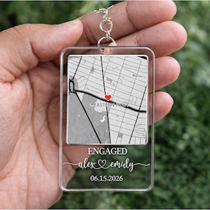 May include: Clear acrylic keychain with a map design, a red heart, and the text "201 EASTERN PKWY." The keychain also features the words "ENGAGED" and the names "alex & emily" with the date "06.15.2026."