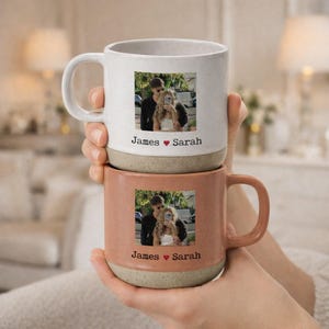 Puede incluir: Dos tazas de cerámica, una blanca y otra melocotón, se sostienen. Cada taza presenta una foto de una pareja y el texto "James ❤️ Sarah". Las tazas tienen una base moteada de tonos neutros.