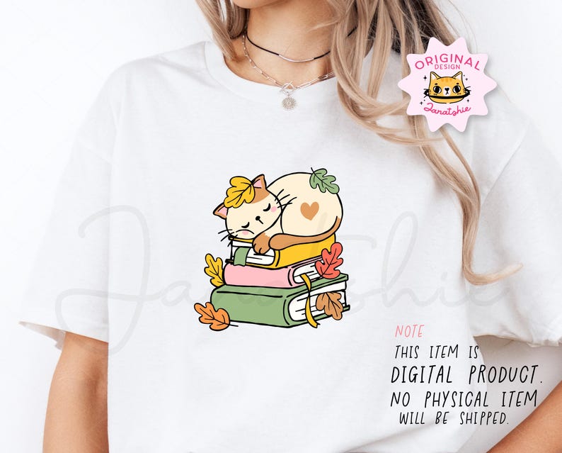 Op de afbeelding: Wit T-shirt met een cartoonkat die op boeken slaapt, versierd met herfstbladeren. De kat is cr&egrave;mekleurig met een geel blad op zijn hoofd en een hart op zijn zij. De tekst op het shirt luidt: "NOTE THIS ITEM IS DIGITAL PRODUCT. NO PHYSICAL ITEM WILL BE SHIPPED."