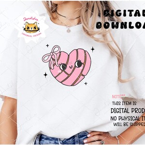 K&ouml;nnte beinhalten: Ein wei&szlig;es T-Shirt mit einem rosafarbenen herzf&ouml;rmigen Geb&auml;ckdesign. Das Geb&auml;ck hat ein s&uuml;&szlig;es Gesicht und ist mit rosa Streifen verziert. Der Text "NOTE** THIS ITEM IS DIGITAL PRODUCT. NO PHYSICAL ITEM WILL BE SHIPPED." ist auf das T-Shirt gedruckt.