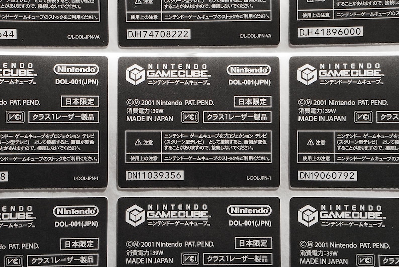 May include: Close-up of six black Nintendo GameCube game labels with white text. The labels include the Nintendo logo, the text "GameCube", and the text "DOL-001(JPN)". The labels also include the text "Japan Limited", "Class 1 Laser Product", and "Made in Japan".
