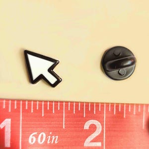 K&ouml;nnte beinhalten: Ein schwarz-wei&szlig;er Emaille-Pin in Form eines Cursors. Der Pin ist etwa 2,5 cm lang. Der Pin hat einen schwarzen Rand und ein wei&szlig;es Innenteil. Die R&uuml;ckseite des Pins ist ein schwarzer, runder Pin mit einem Verschluss.