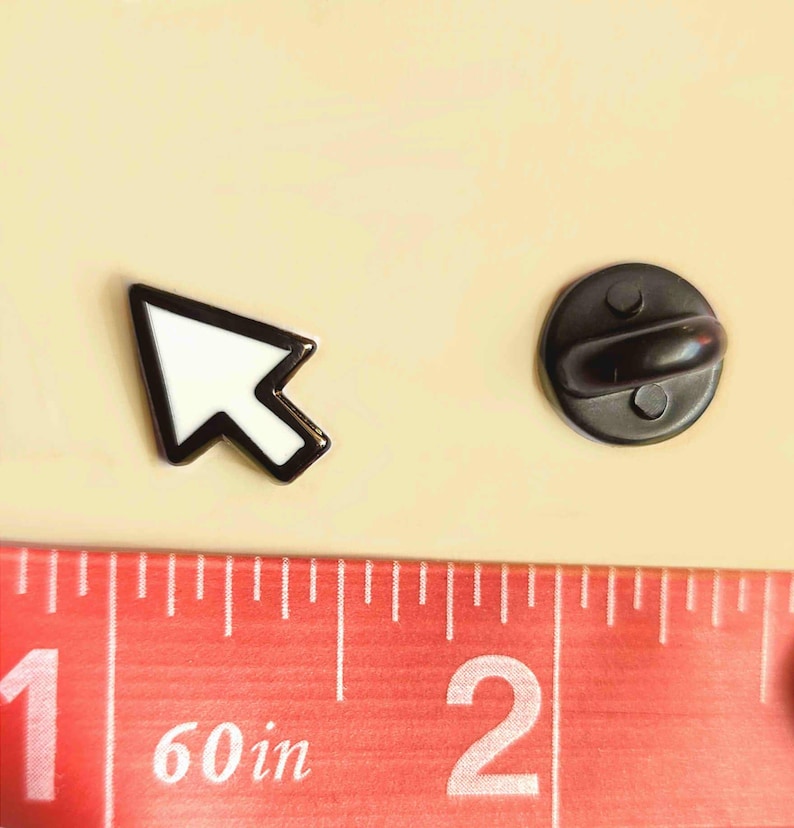 K&ouml;nnte beinhalten: Ein schwarz-wei&szlig;er Emaille-Pin in Form eines Cursors. Der Pin ist etwa 2,5 cm lang. Der Pin hat einen schwarzen Rand und ein wei&szlig;es Innenteil. Die R&uuml;ckseite des Pins ist ein schwarzer, runder Pin mit einem Verschluss.