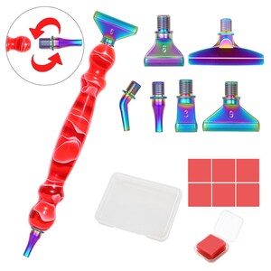May include: A diamond painting pen set with a red and white marbled handle, various iridescent tips, a clear plastic container, and red wax squares. The tips are labeled with numbers. The set includes a small clear container with red wax.