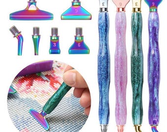 Puede incluir: Un juego de cuatro bolígrafos para pintura de diamantes con mangos de resina brillante y marmolada en azul, rosa, verde y morado, junto con seis puntas metálicas intercambiables con acabado arcoíris, incluyendo varias formas planas y anguladas.