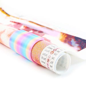 May include: A rolled diamond painting canvas secured with a pastel rainbow-colored plastic clip. The canvas features a grid of small colored dots and a printed legend with symbols and numbers including 3688, 3712, 3727, 3777, 3802, and 3833.