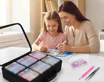 Puede incluir: Un estuche de almacenamiento negro con tapa transparente que contiene varios recipientes rectangulares pequeños llenos de cuentas de colores, junto con un bolígrafo aplicador rosa, pinzas de metal y una bandeja con cuentas rosas para pintura de diamantes.