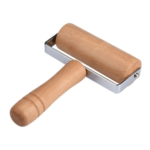 May include: A wooden rolling pin with a metal frame and a wooden handle. The rolling pin is used for baking and is approximately 25 cm long.