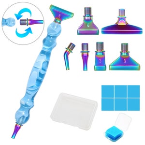 May include: A diamond painting pen set with a clear blue handle and iridescent tips. The set includes multiple interchangeable tips, a small clear container, and blue adhesive squares. The pen handle has a swirling white design.