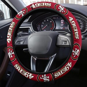 May include: Red, black, and gold steering wheel cover with the San Francisco 49ers logo and the team name "49ers" repeated around the cover.