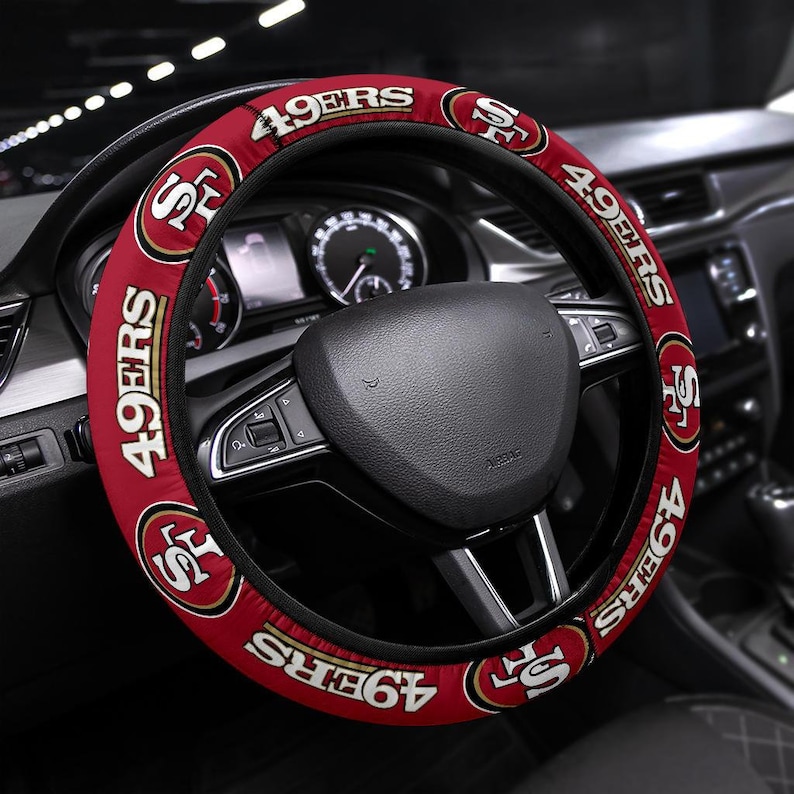 May include: Red and gold steering wheel cover with the San Francisco 49ers logo and team name.