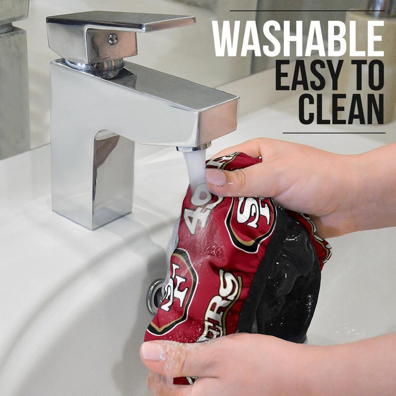 May include: A red and black fabric shower cap with the San Francisco 49ers logo and the text "49ers" is being rinsed under a faucet. The text "WASHABLE EASY TO CLEAN" is visible in the upper right corner of the image.