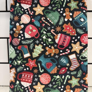 May include: A dark blue fabric book cover with a festive Christmas pattern. The design includes gingerbread men, mugs, stars, candy canes, ornaments, and holly leaves in red, green, and white. The cover is rectangular.