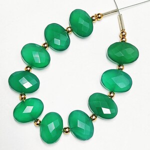 Puede incluir: Una hebra de cuentas de piedras preciosas verdes con separadores dorados. Las cuentas son de forma ovalada y tienen un acabado facetado.