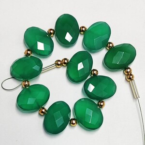 Puede incluir: Una hebra de cuentas de piedras preciosas verdes con separadores dorados. Las cuentas son de forma ovalada y tienen un acabado facetado.