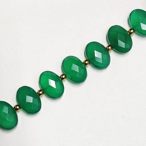 Puede incluir: Un collar hecho de piedras preciosas ovaladas verdes separadas por cuentas doradas.