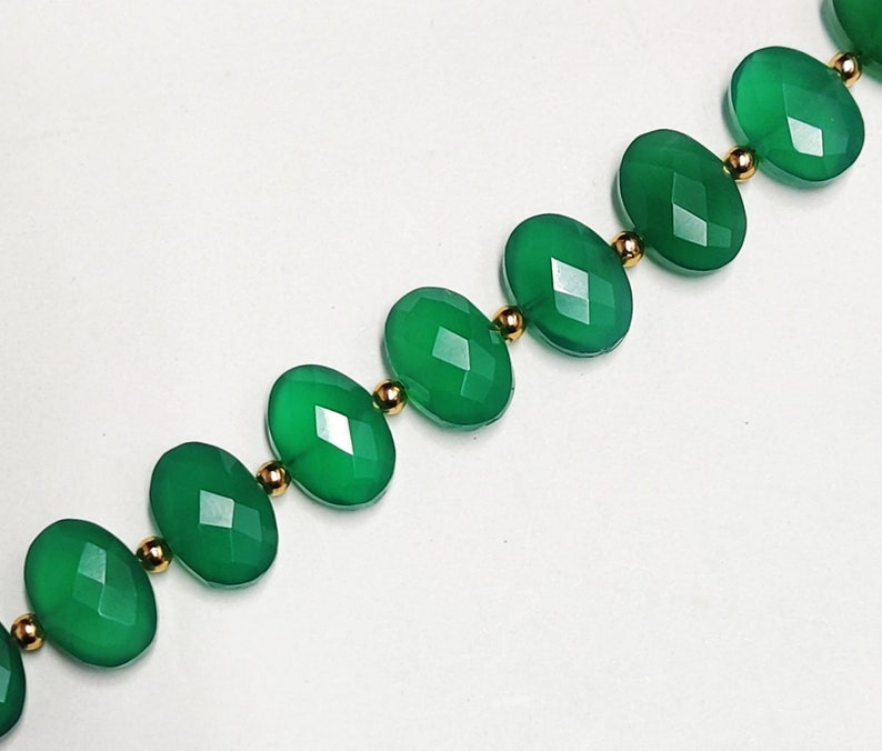 Puede incluir: Un collar hecho de piedras preciosas ovaladas verdes separadas por cuentas doradas.