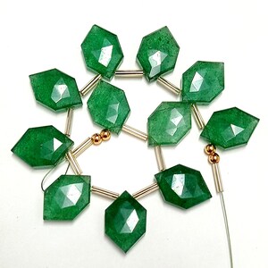 May include: A strand of green gemstone beads with gold spacers. The beads are faceted and have a diamond shape.