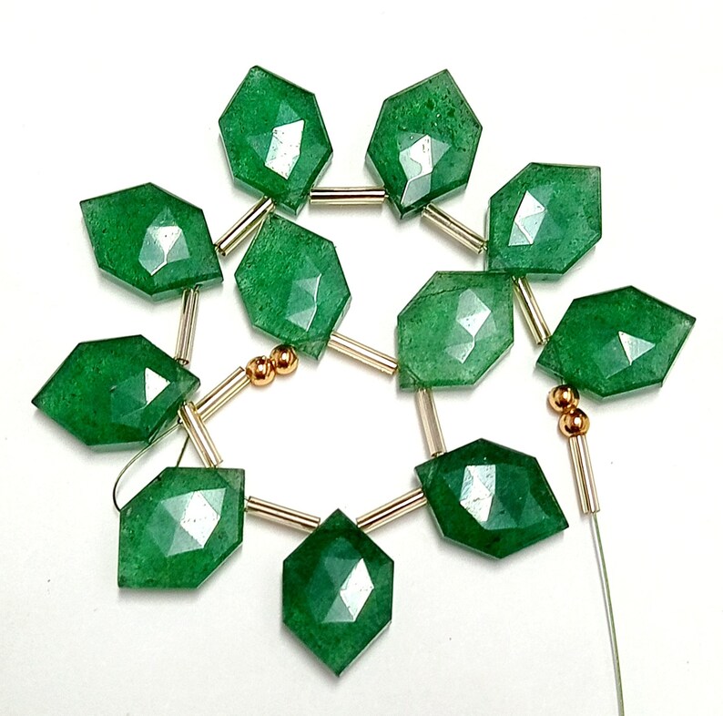 May include: A strand of green gemstone beads with gold spacers. The beads are faceted and have a diamond shape.
