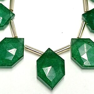 May include: A necklace with six faceted green gemstone beads separated by gold spacers. The beads are in a diamond shape.