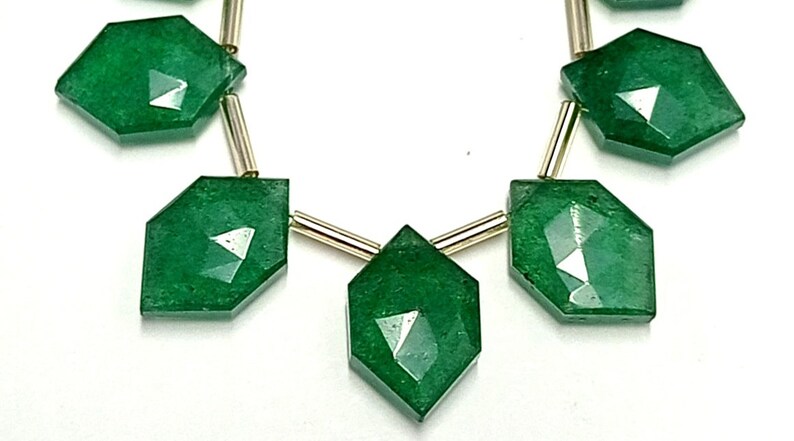 May include: A necklace with six faceted green gemstone beads separated by gold spacers. The beads are in a diamond shape.