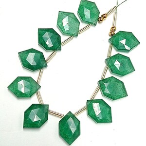 May include: A strand of green gemstone beads with faceted edges, separated by gold spacers. The beads are strung on a clear thread.