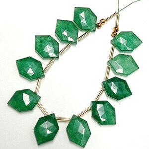 May include: A strand of green gemstone beads with gold spacers. The beads are faceted and have a slightly irregular shape.