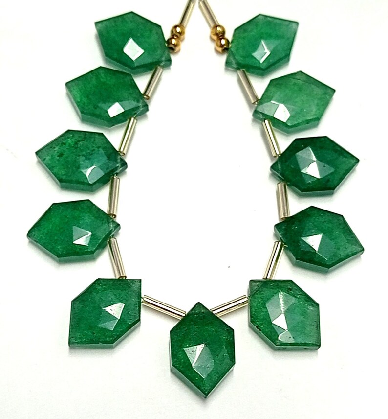 May include: A strand of green gemstone beads with faceted, diamond-shaped beads. The beads are strung on gold-toned wire.