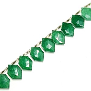 May include: A strand of green gemstone beads with a faceted, diamond-shaped design. The beads are strung on a silver wire.