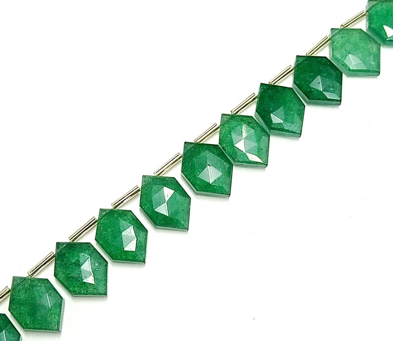 May include: A strand of green gemstone beads with a faceted, diamond-shaped design. The beads are strung on a silver wire.