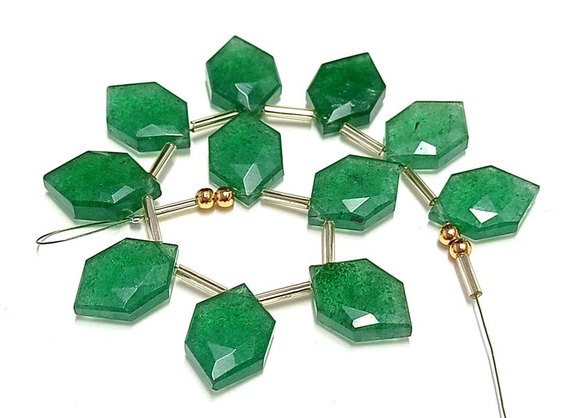 May include: A strand of green gemstone beads with gold spacers. The beads are faceted and have a slightly irregular shape. The strand is strung on a wire.